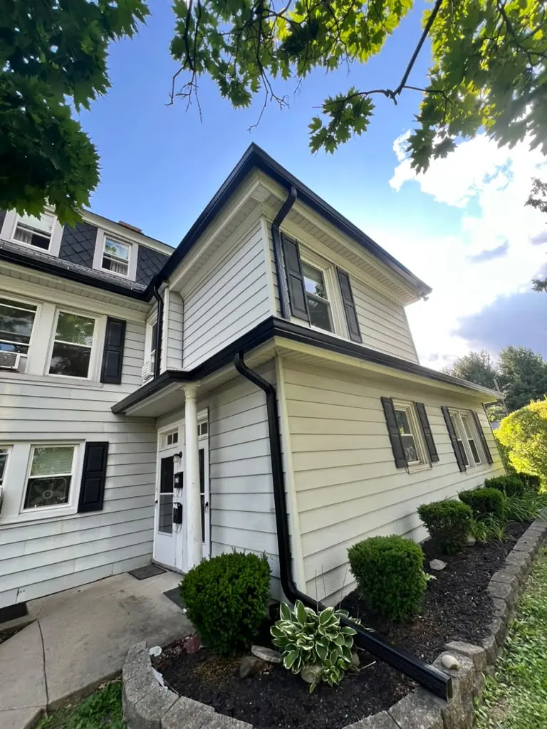 Black seamless gutters and downspouts on a white colonial