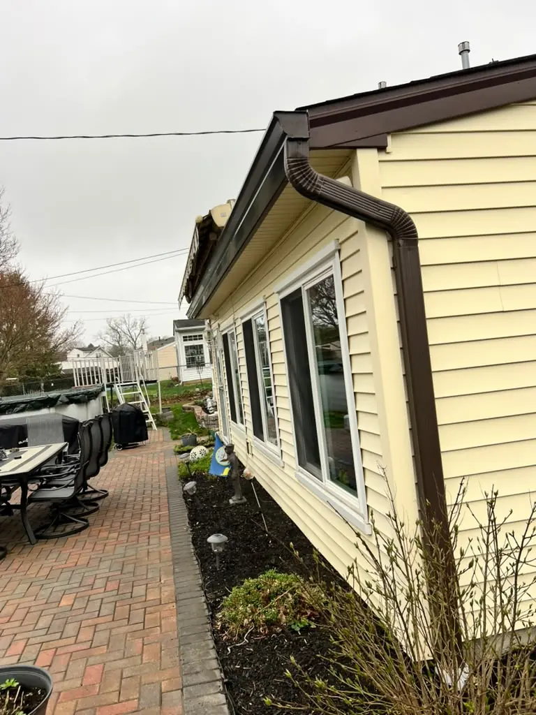 Brown seamless gutters on a home with yellow siding