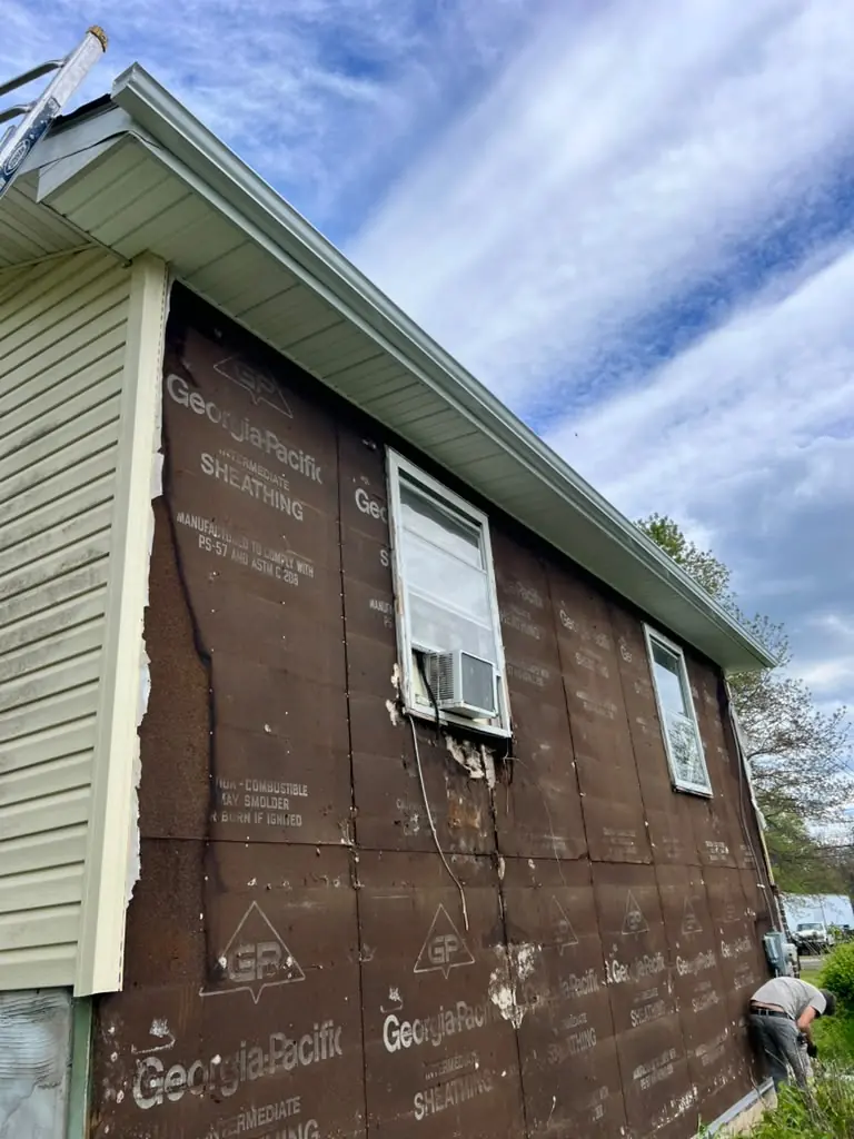 Siding replacement in progress over weather barrier